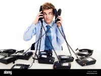 young-man-in-the-office-and-answering-several-phones-at-the-same-time-G0MP96-4224908181.jpg